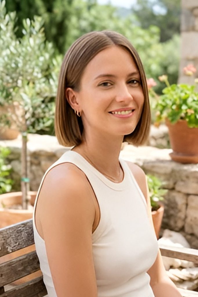 Smooth chin-length light brown bob with small earrings in a sunny garden