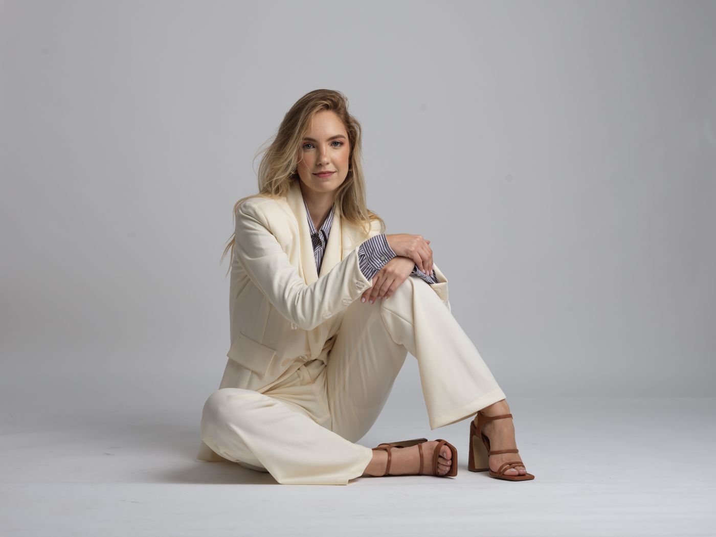 Elegant woman seated in a white tailored suit