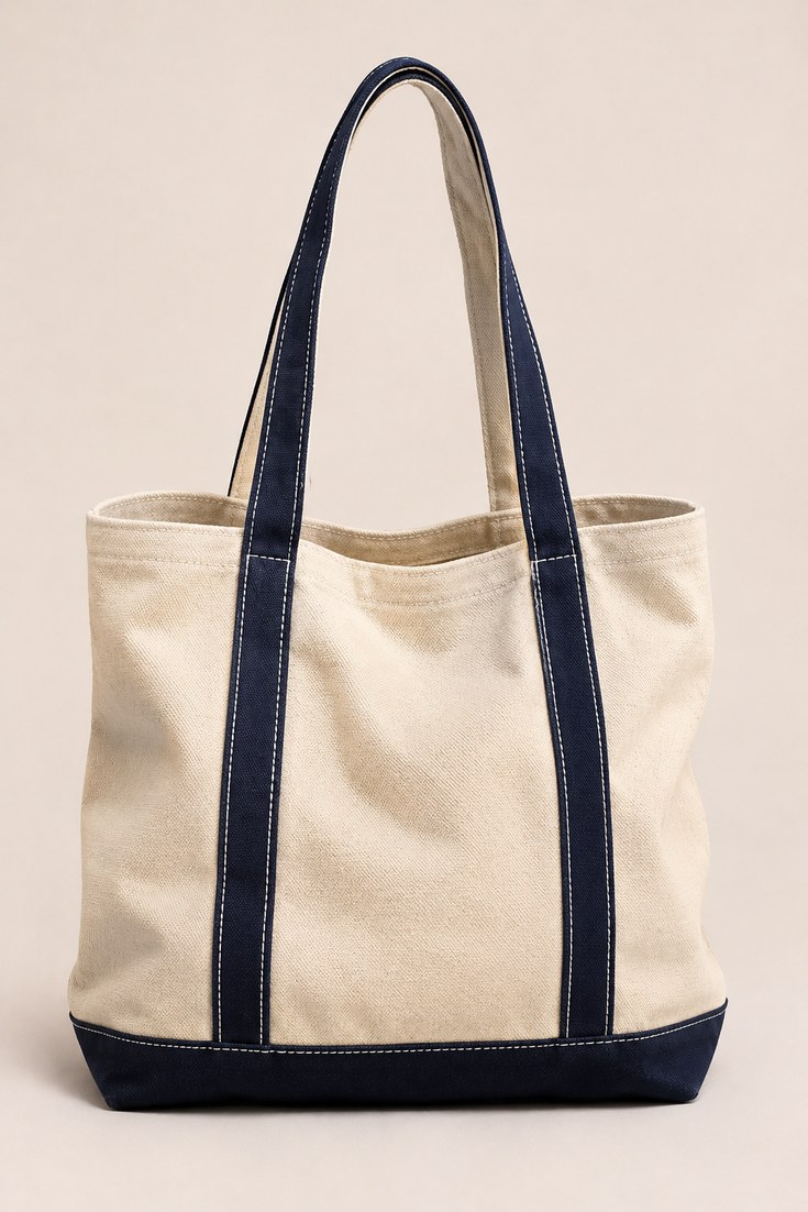 Natural cream heavyweight canvas tote bag with navy stitched handles on a soft ivory backdrop