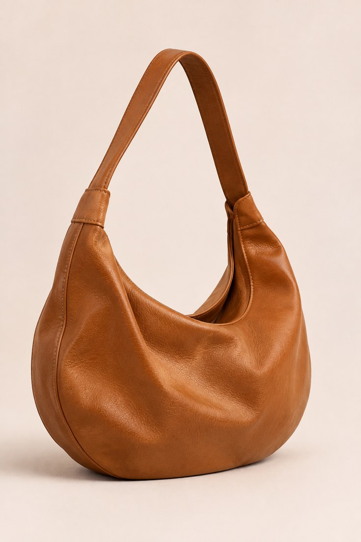 Soft slouchy tan leather hobo shoulder bag with a wide strap on a soft ivory backdrop