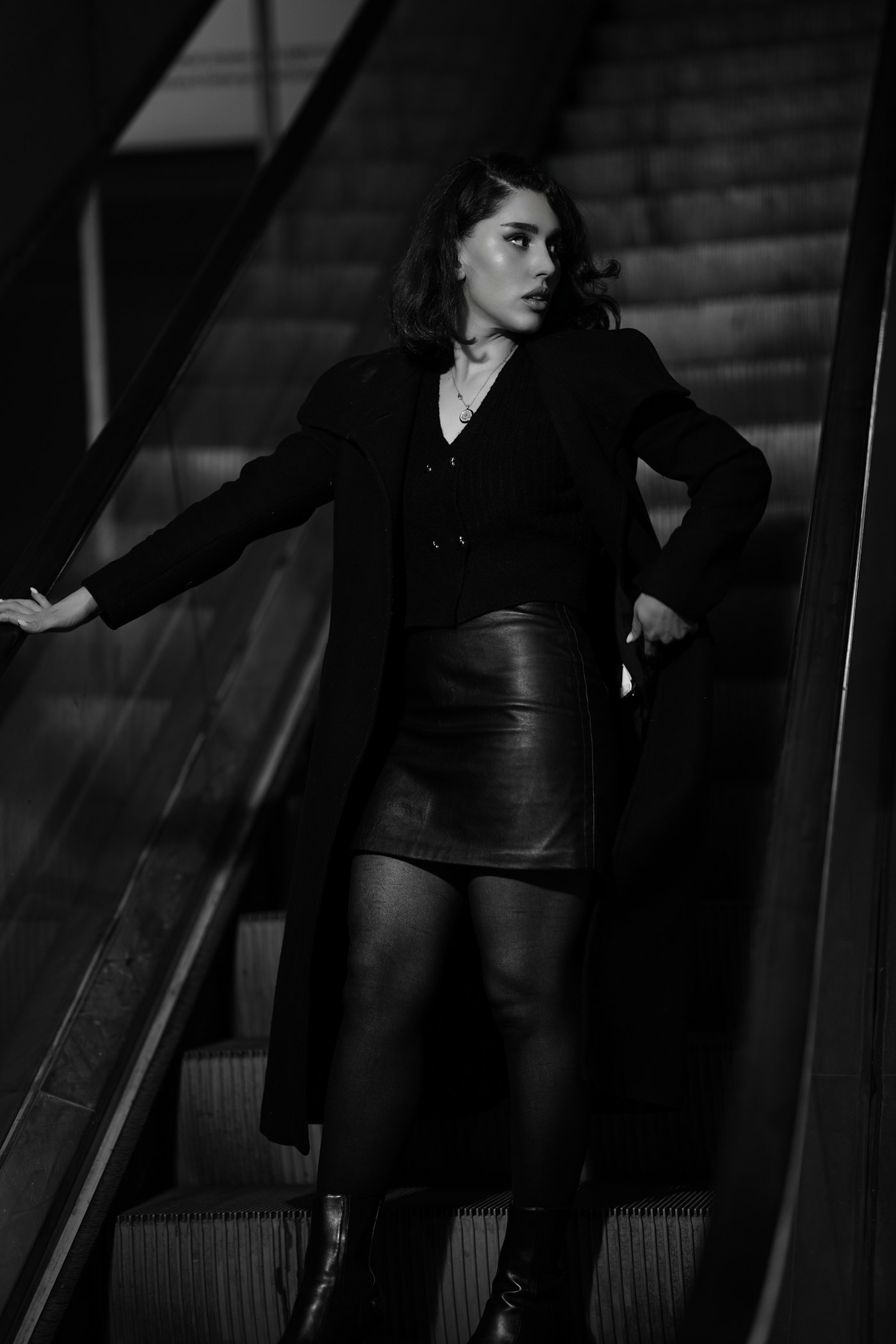 Woman in a black coat and leather skirt on an escalator