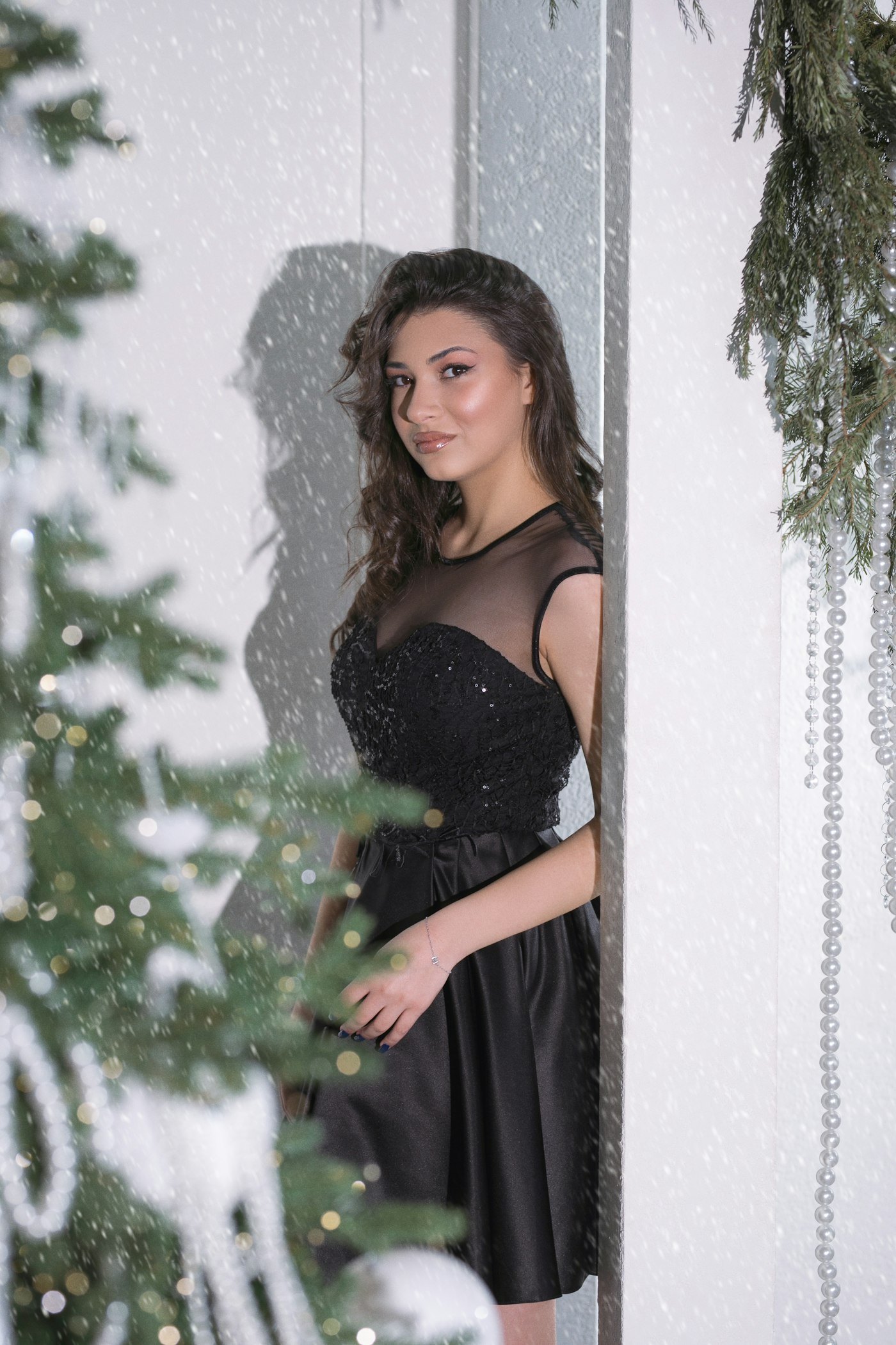 Woman in a black dress sitting by a Christmas tree