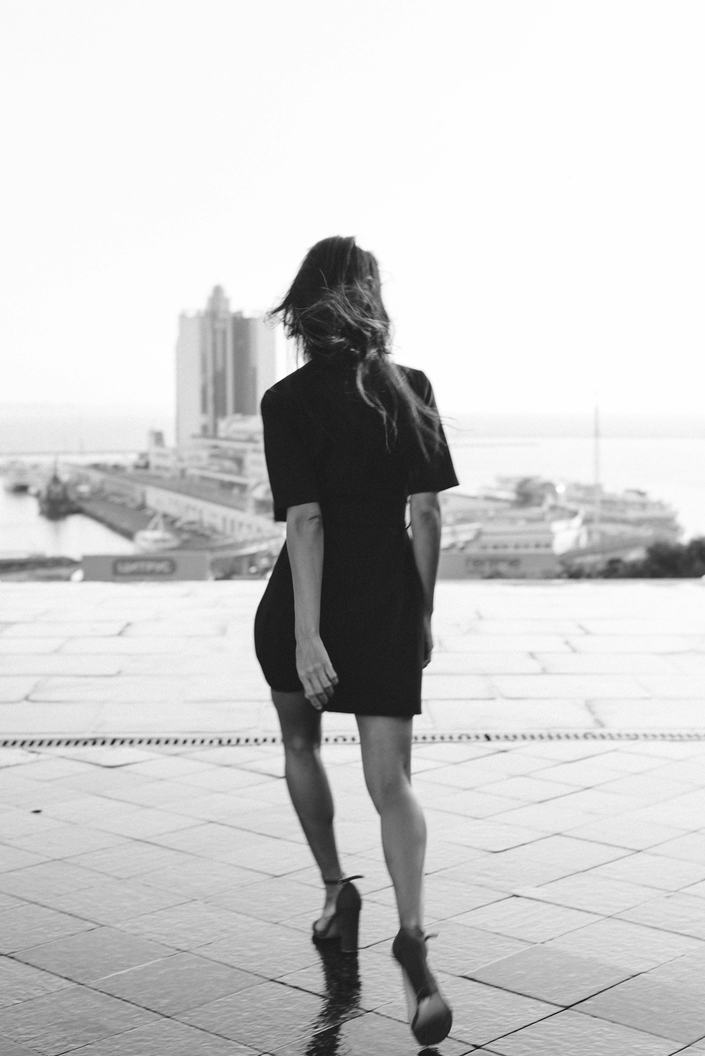 Woman in a black dress walking along a city sidewalk