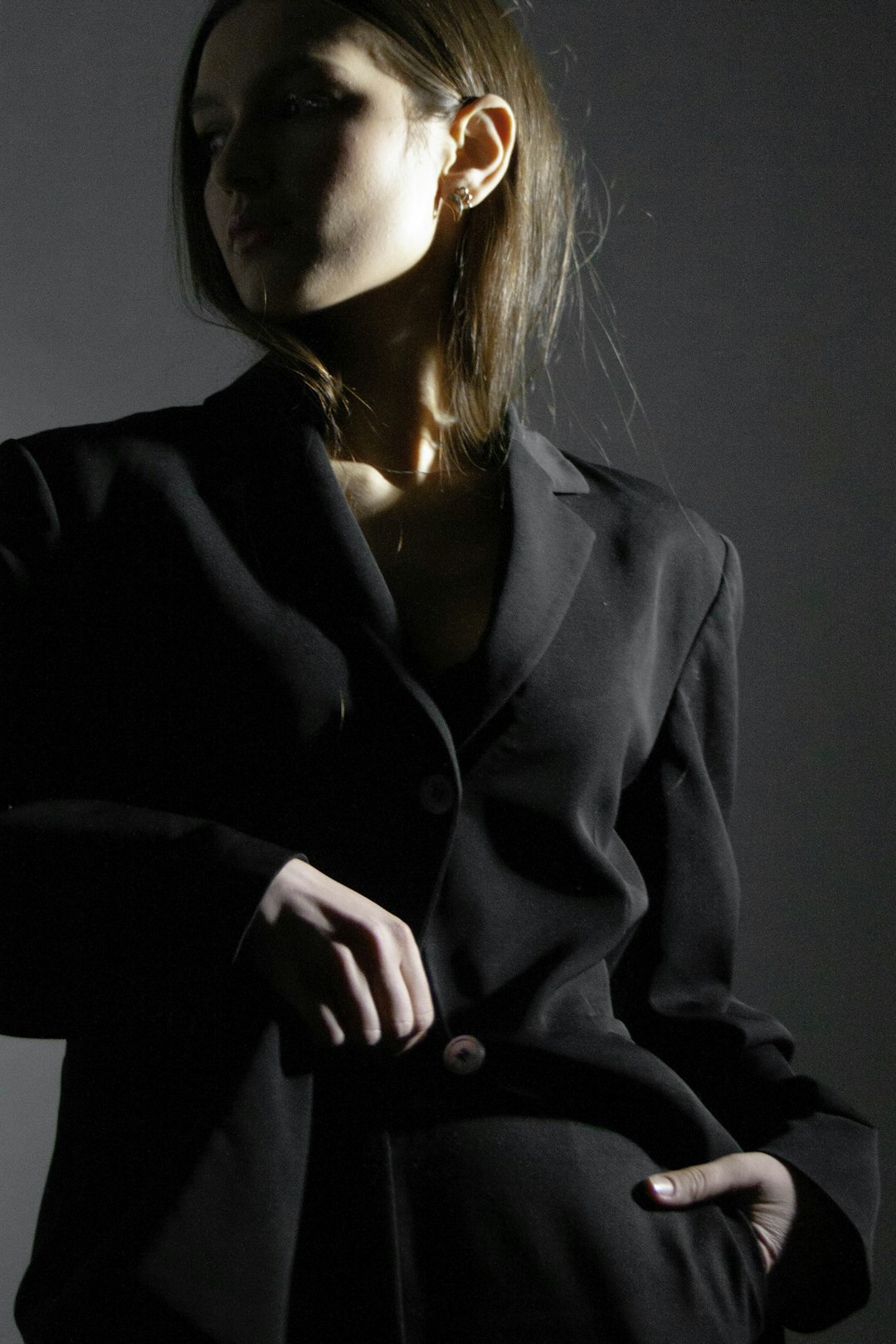 Woman in a black suit posing against a neutral background