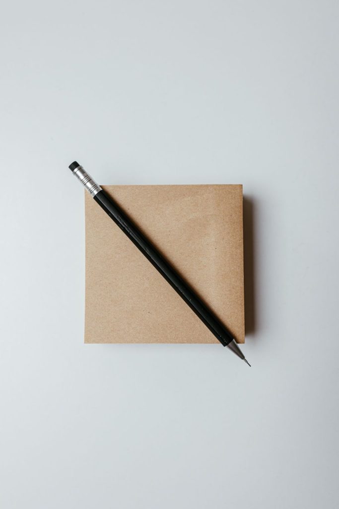 Blank kraft paper notebook with a black pen on a white table, ready for a simple menu chart