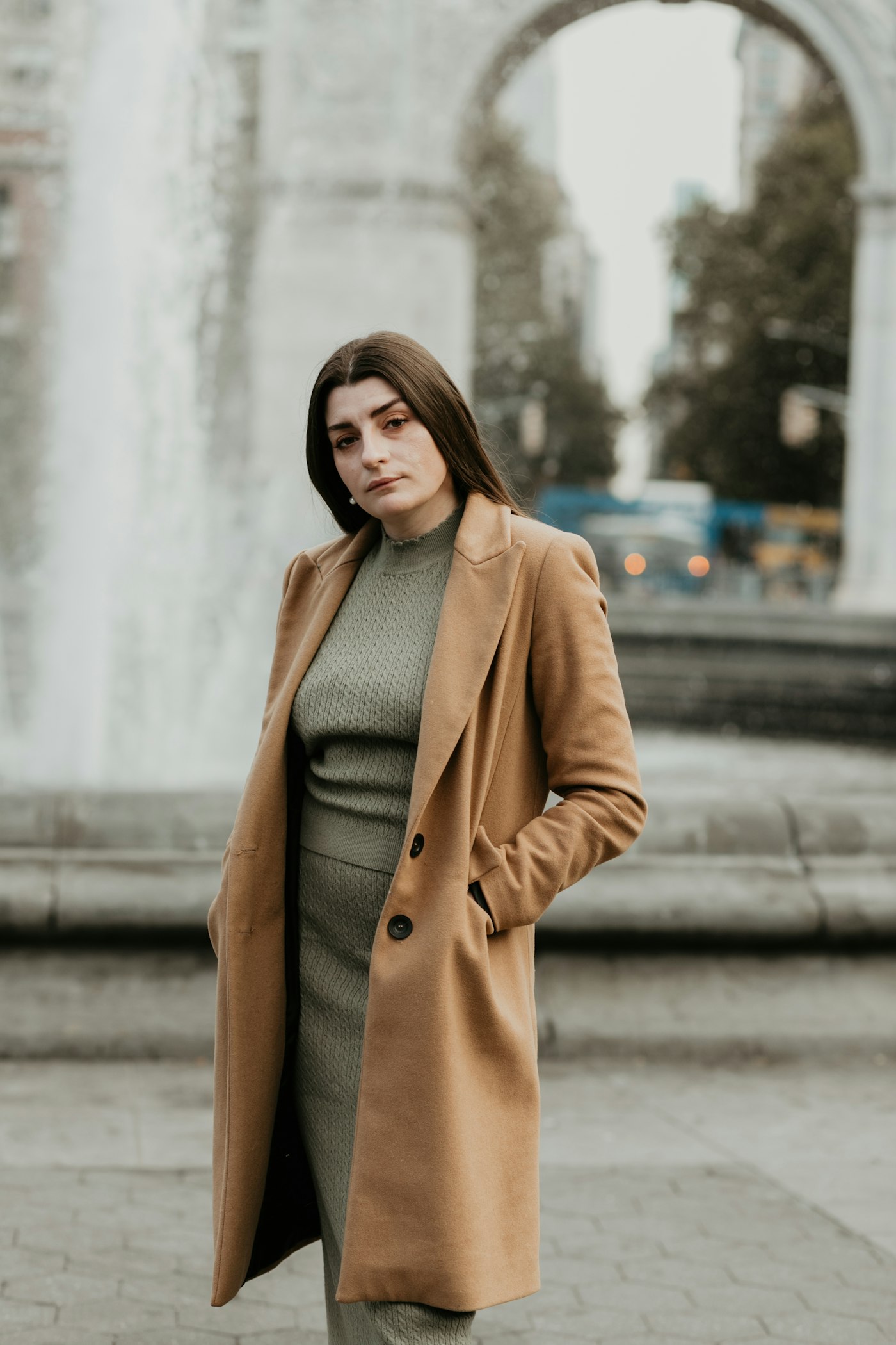 Woman in a brown wool coat standing on a city sidewalk