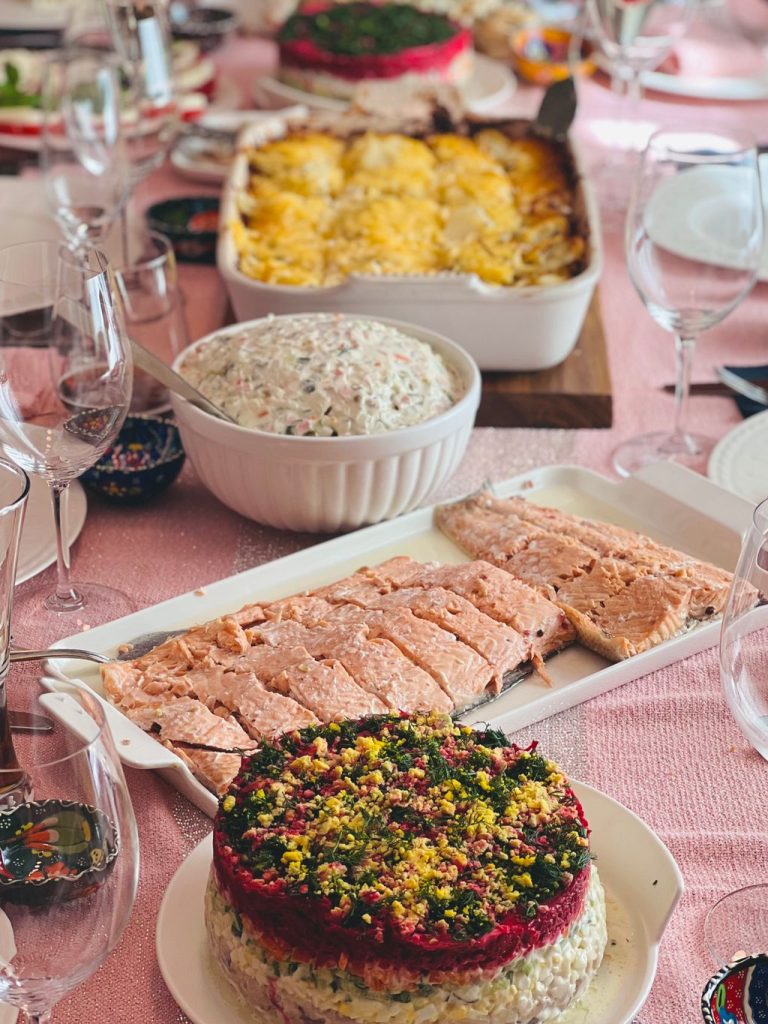 Table laid out buffet style with a baked casserole, creamy salad and layered dishes ready for guests to serve themselves
