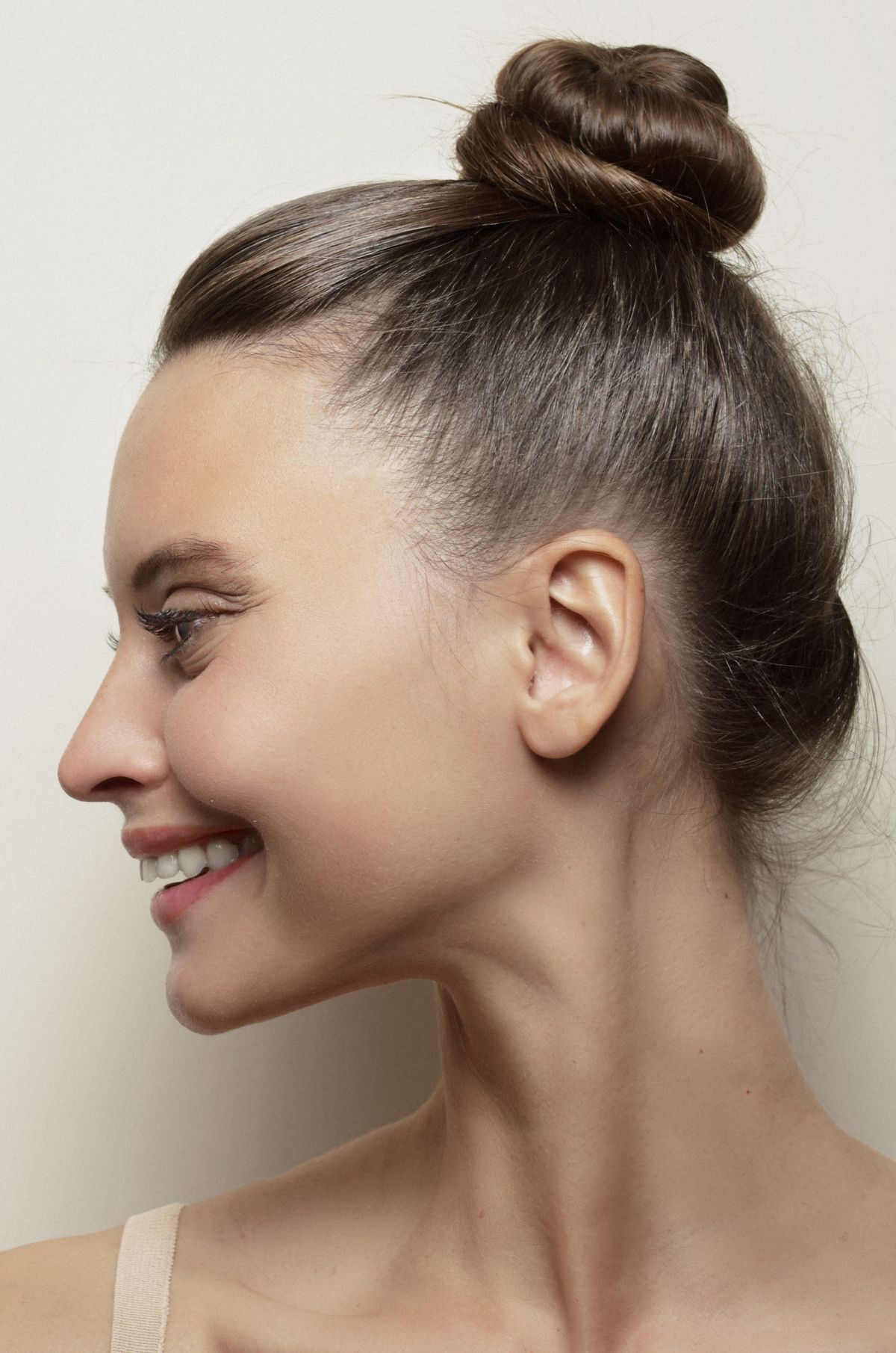 Woman in profile smiling, with her hair pulled smoothly back into a tight, sleek bun at the top of her head