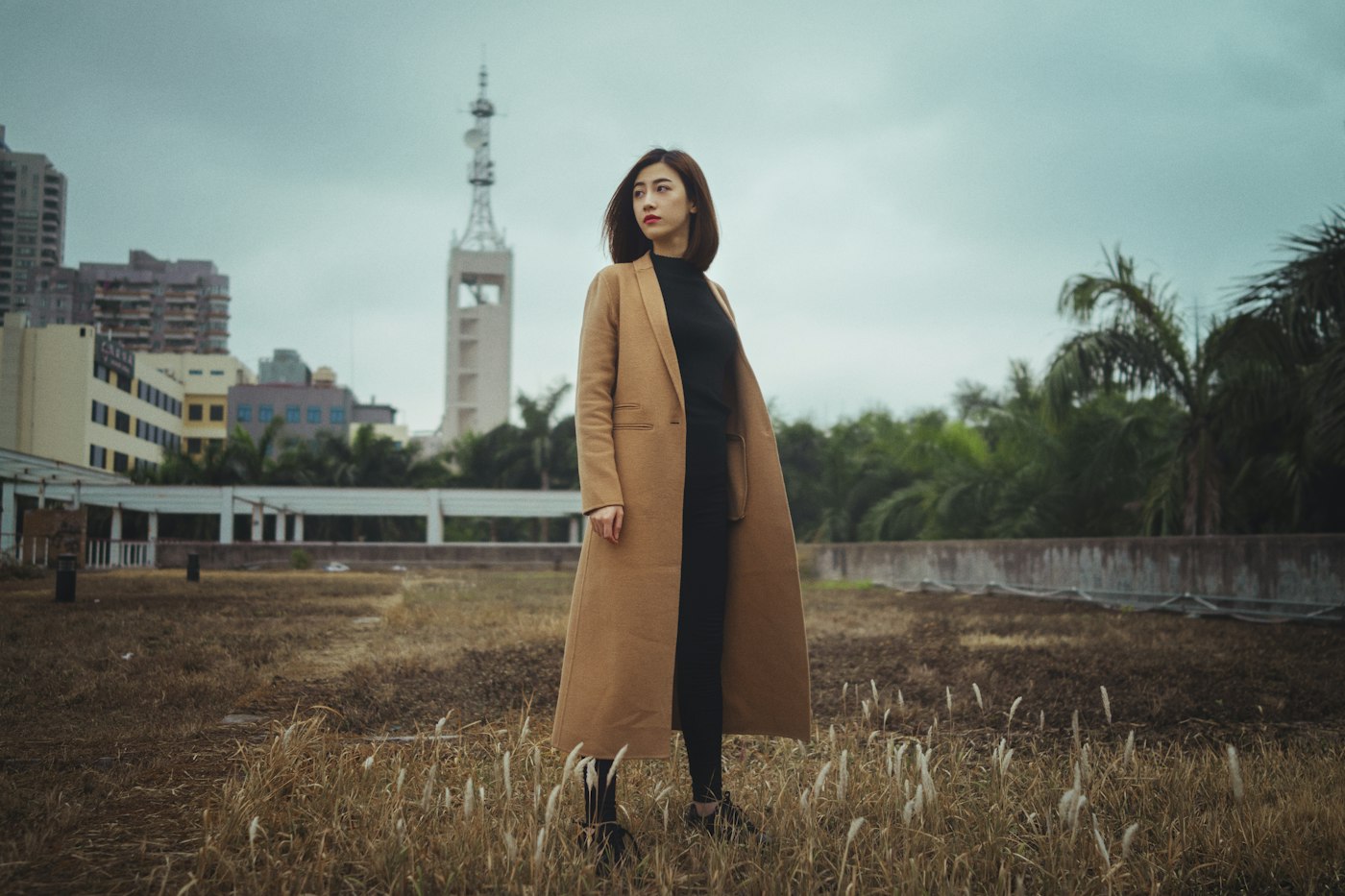 Woman wearing a brown coat standing on brown grass