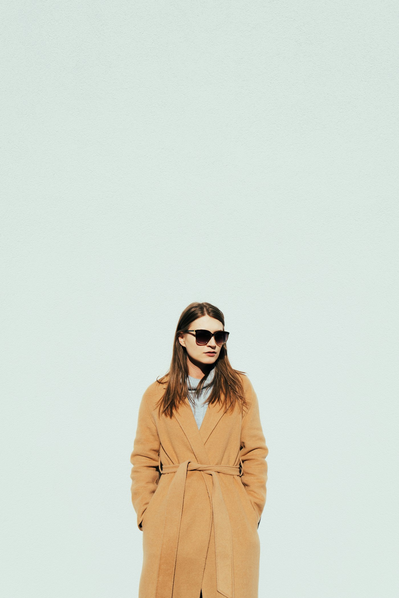 Woman in a tan coat and sunglasses
