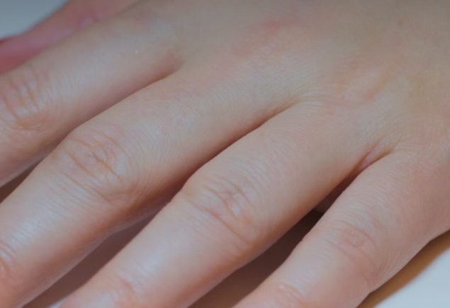 Hand with red painted nails and a gold watch, a classic red Christmas manicure