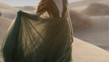 Woman in a green dress standing outdoors as Christmas outfit inspiration