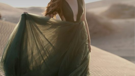 Woman in a green dress standing outdoors as Christmas outfit inspiration