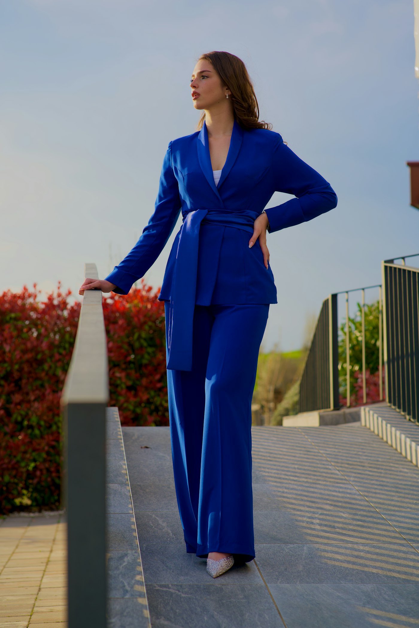 Woman in a blue suit standing on a ledge, showing a strong blue in tailoring
