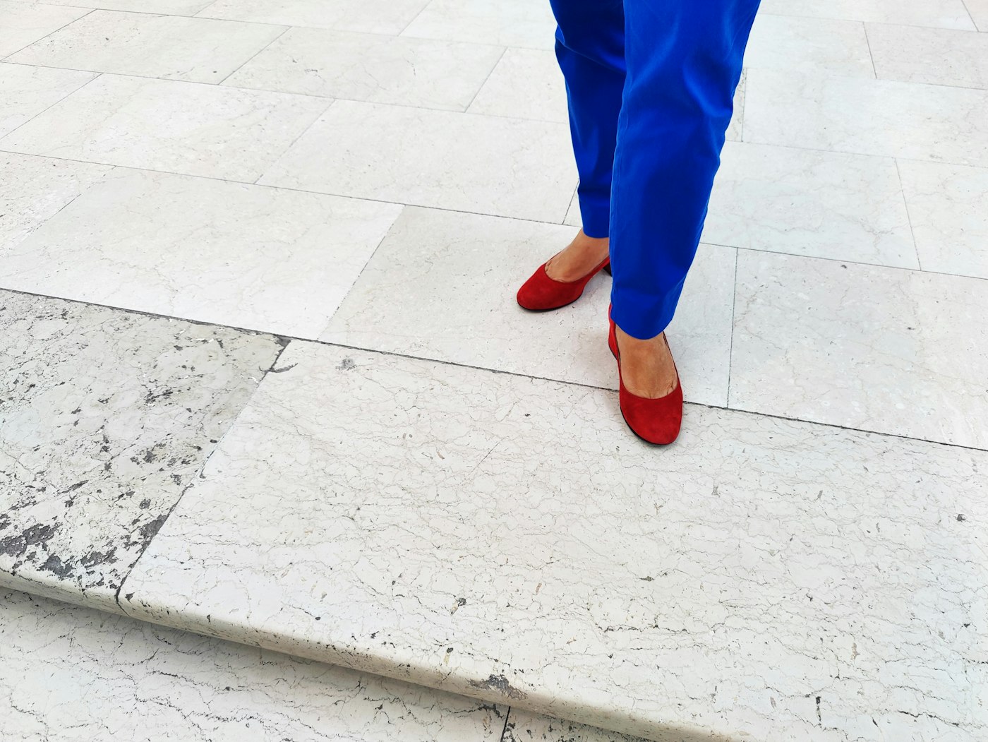 Woman in a tan top and bright blue trousers, a neutral top with cobalt trousers