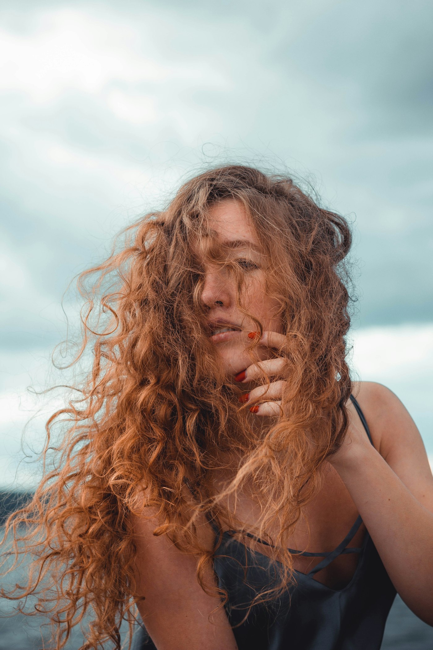 Woman with red curly hair standing on a beach