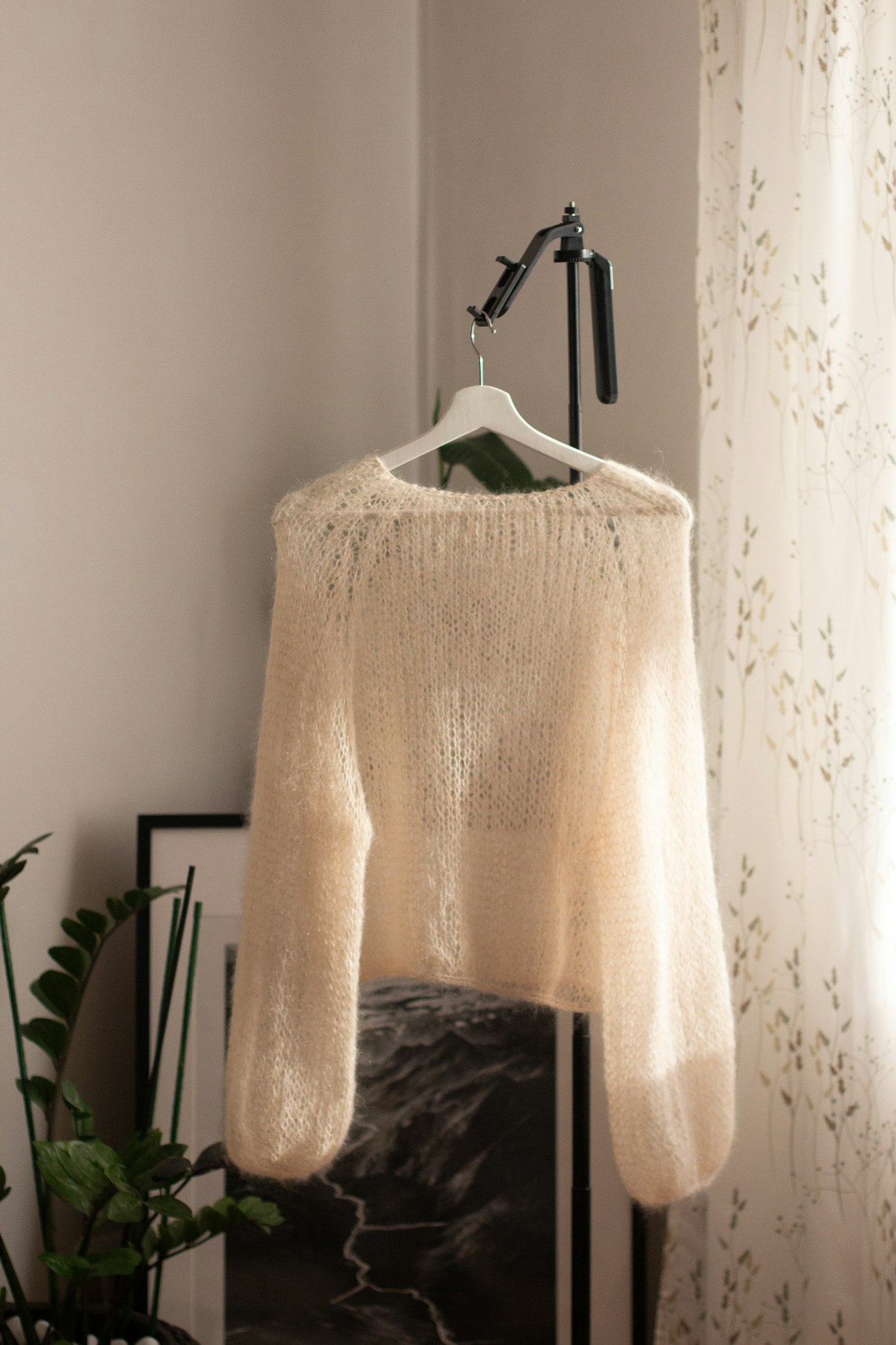 Cream fuzzy knit sweater hanging on a hanger