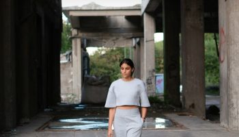 Woman in grey trousers and a light top walking outdoors, styled for a grey knit and trousers outfit