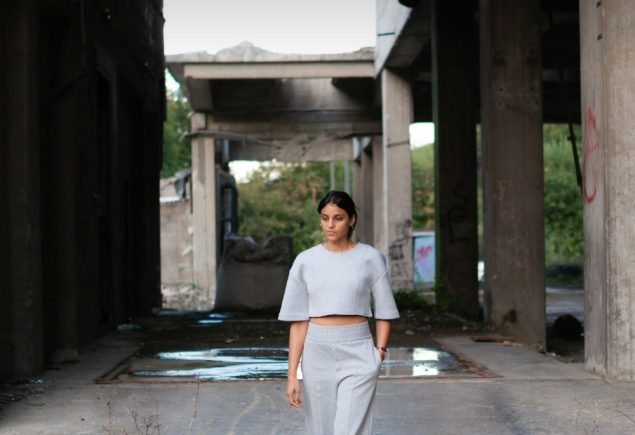 Woman in grey trousers and a light top walking outdoors, styled for a grey knit and trousers outfit
