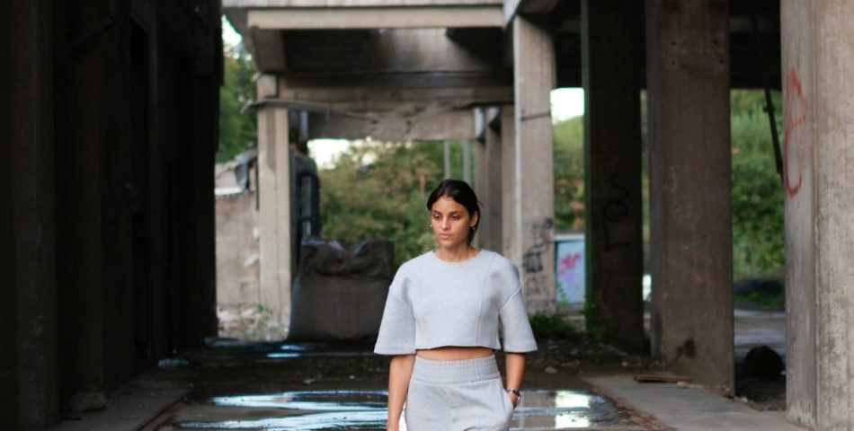 Woman in grey trousers and a light top walking outdoors, styled for a grey knit and trousers outfit