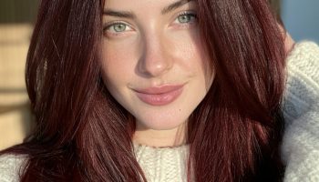 Woman with deep wine burgundy long straight hair in a cream wool sweater