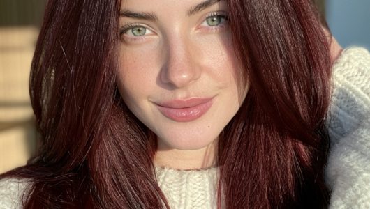 Woman with deep wine burgundy long straight hair in a cream wool sweater
