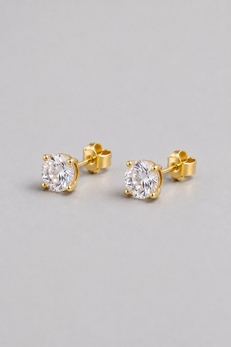 A pair of round brilliant diamond style stud earrings in four prongs on a light grey backdrop