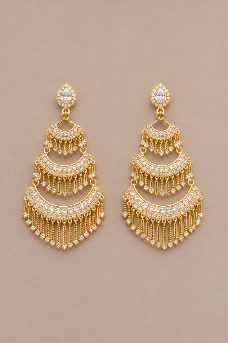 A pair of gold statement chandelier earrings with crystals on a deep taupe backdrop