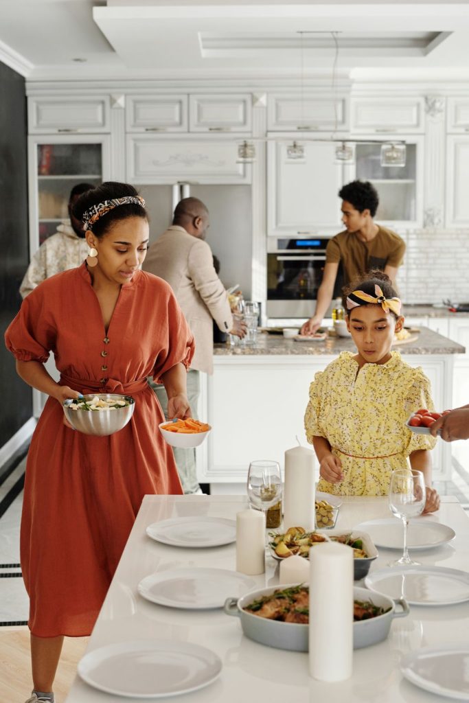 Family members sharing kitchen tasks together, chopping, serving and preparing dishes for a holiday meal
