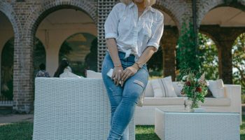 Woman in a white dress shirt and blue jeans standing outdoors