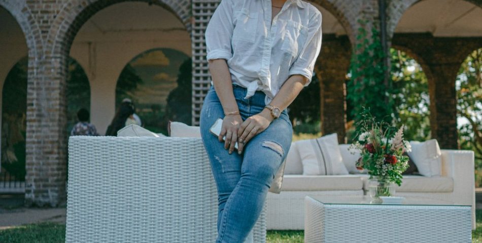 Woman in a white dress shirt and blue jeans standing outdoors