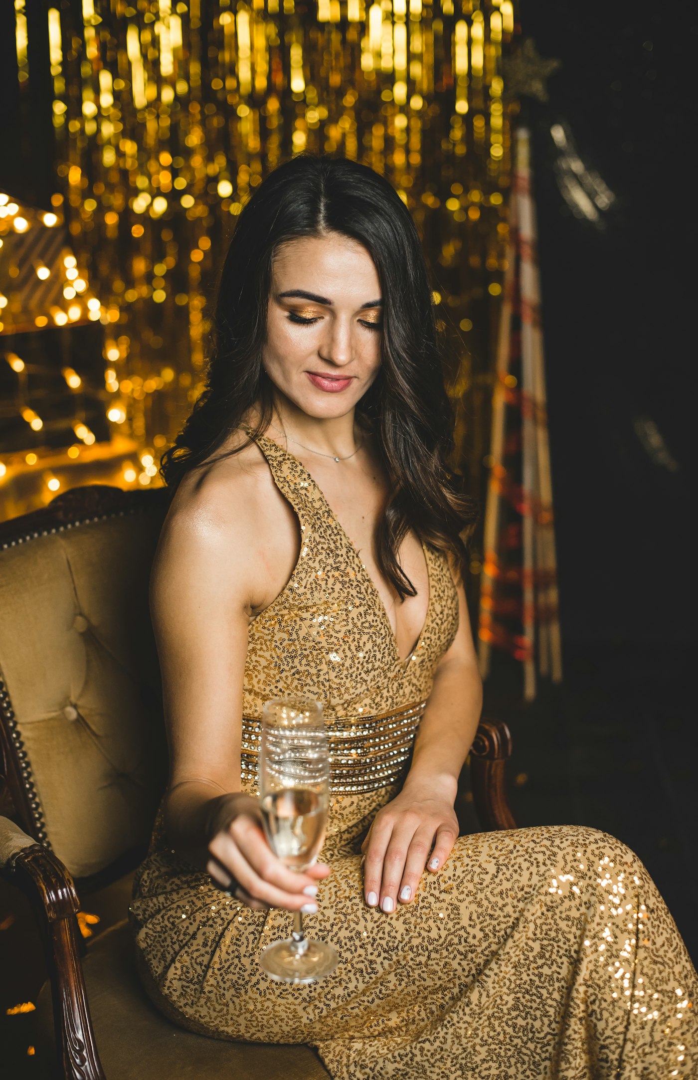 Woman in a gold sleeveless dress sitting on a chair