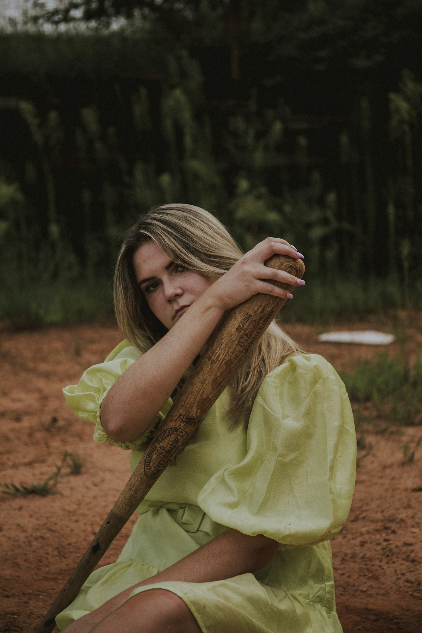 Woman in a green dress sitting on dried leaves