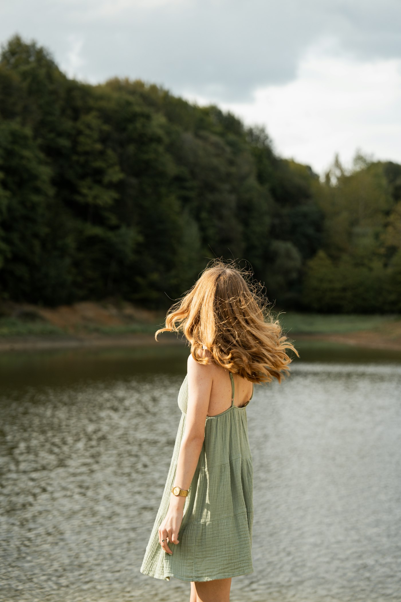 Woman in a green dress walking by a lake