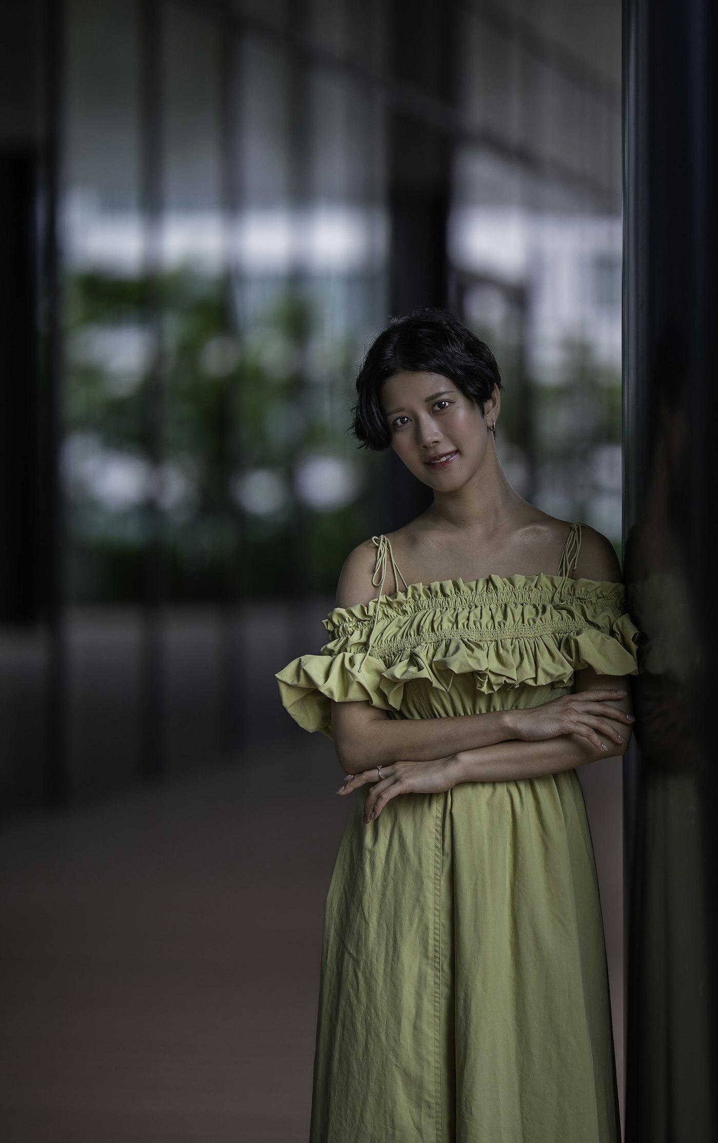 Woman in a green dress leaning on a wall