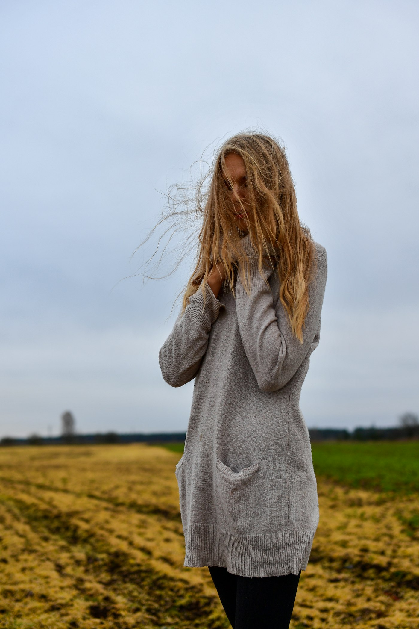 Woman in a grey knit sweater standing in a field