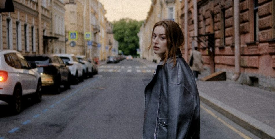 Woman in a black leather jacket on a city street, styled for a leather jacket and jeans outfit