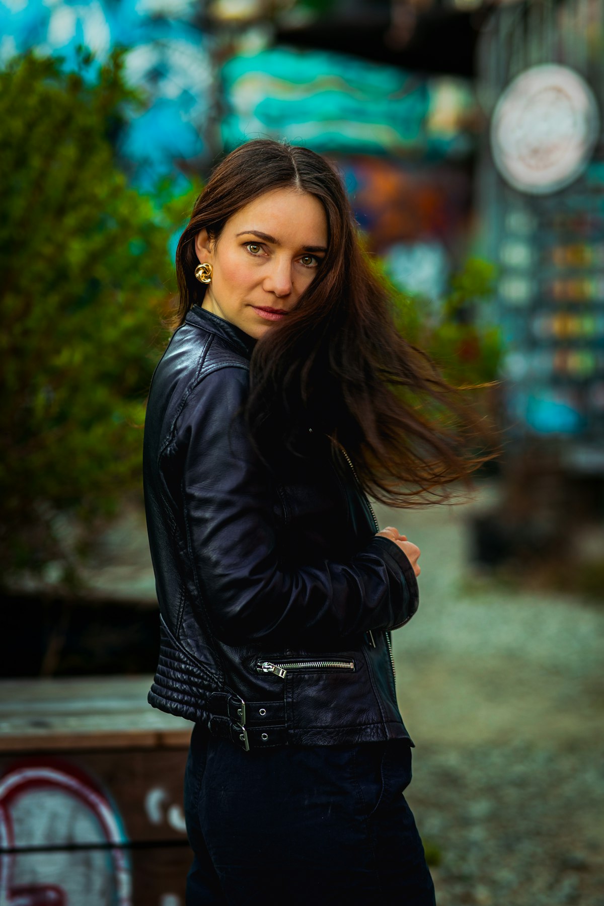 Woman in a black leather jacket with windswept hair outdoors
