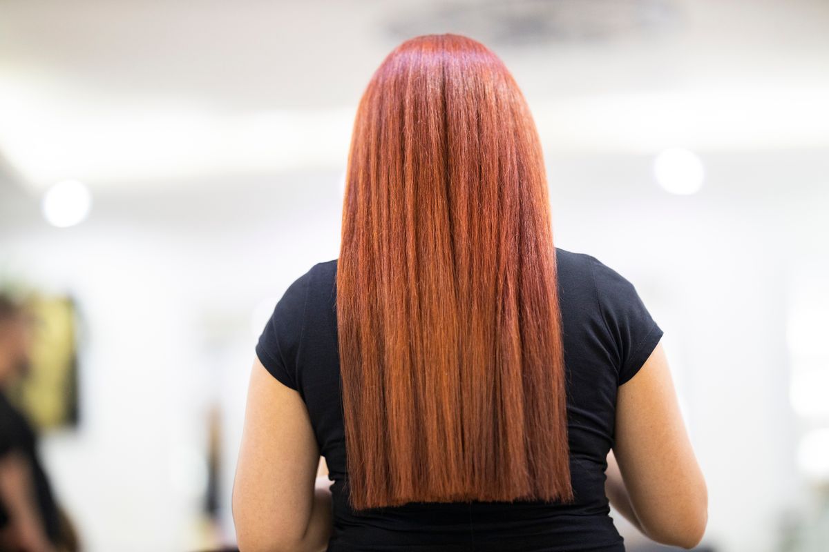 Long straight copper red hair seen from behind on a woman in a black t-shirt