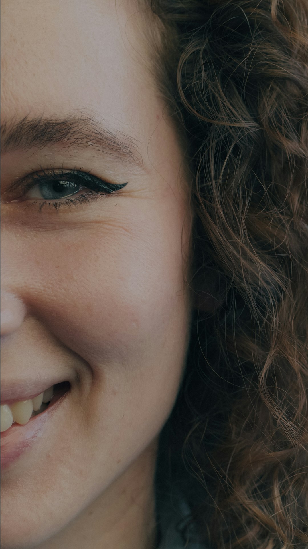 Close-up of a smiling woman with blue eye makeup