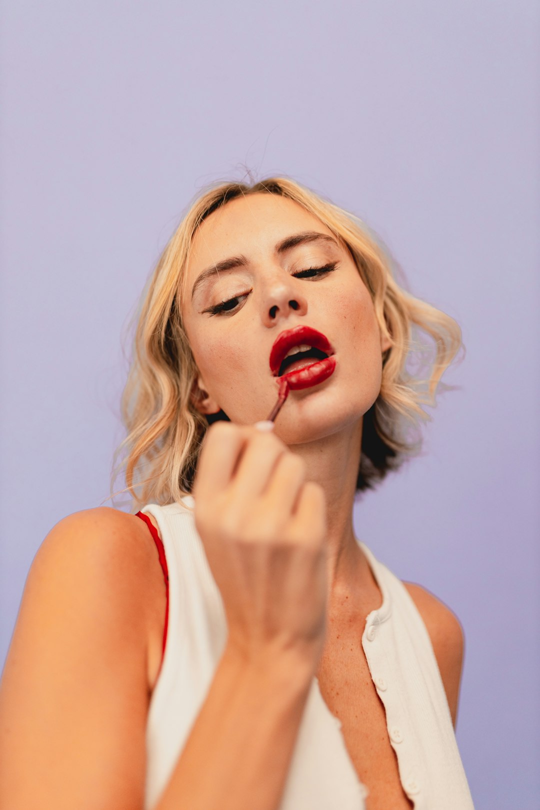 Woman putting lipstick on her lips
