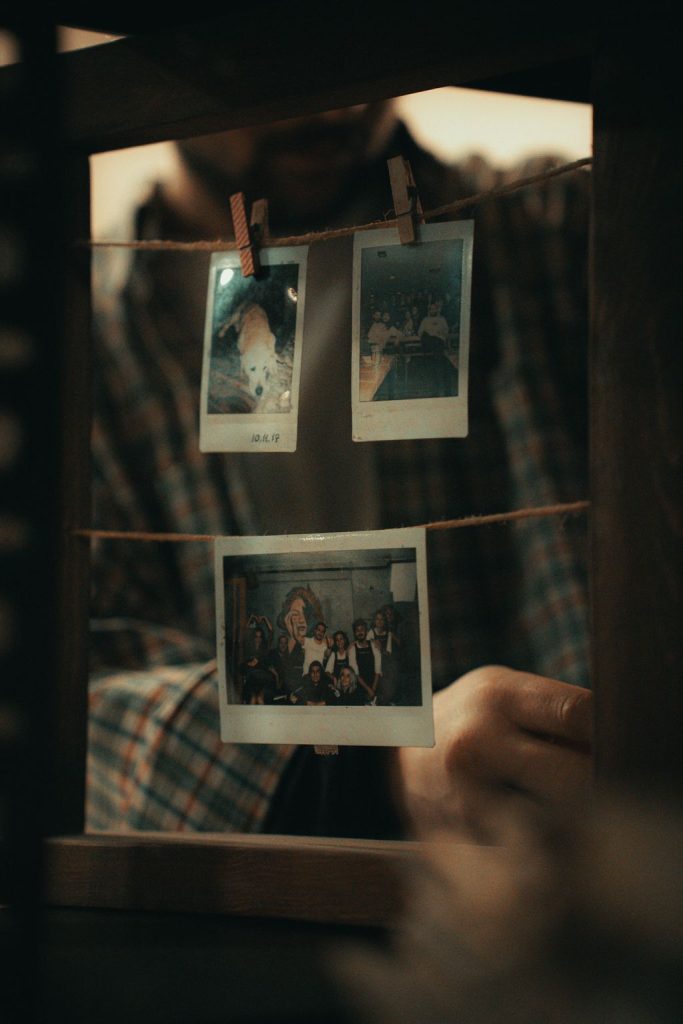 Instant photo prints clipped with wooden pegs to a string line, a simple self-run photo corner display