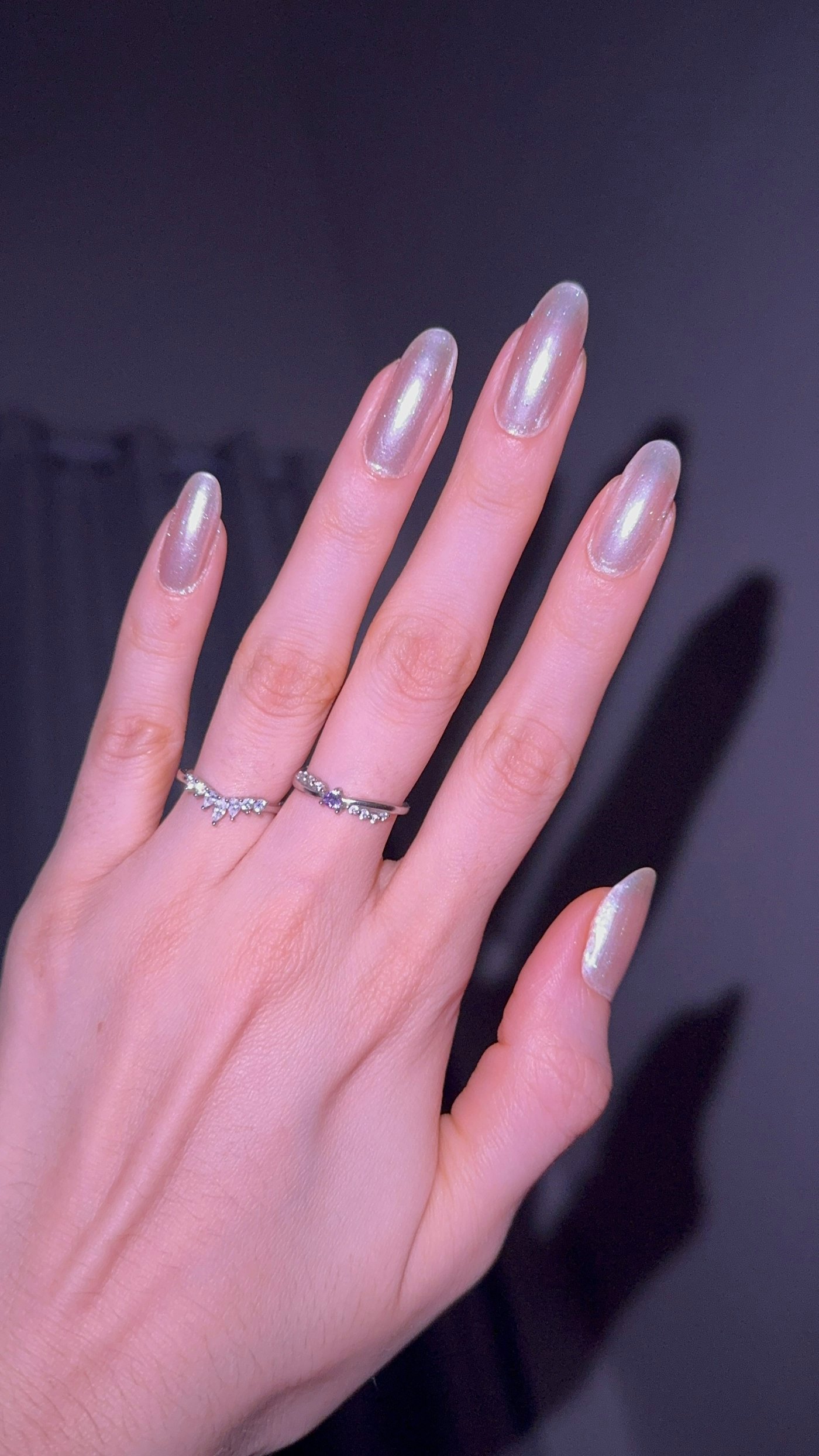 Hand with iridescent nail polish and rings