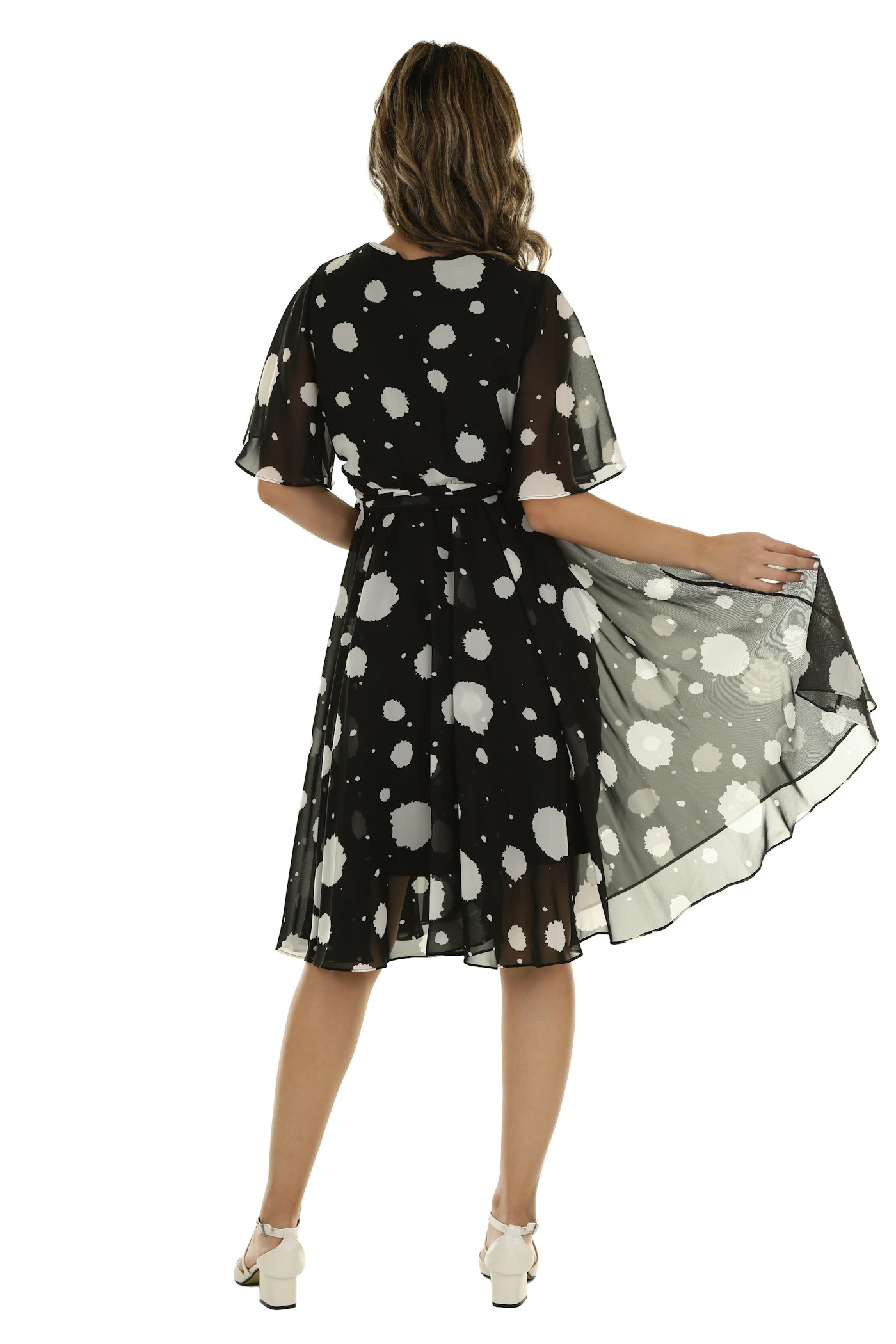 Woman in a black dress with white polka dots holding the skirt