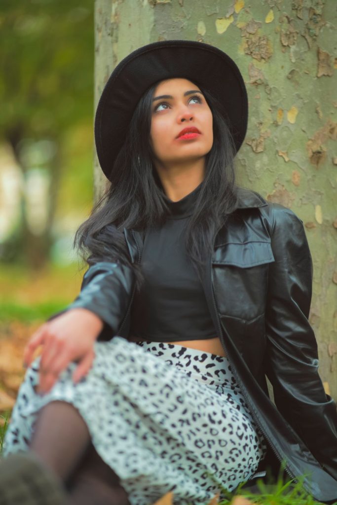 Woman in a black wide-brim hat, a black leather jacket, a black top and a grey leopard print skirt