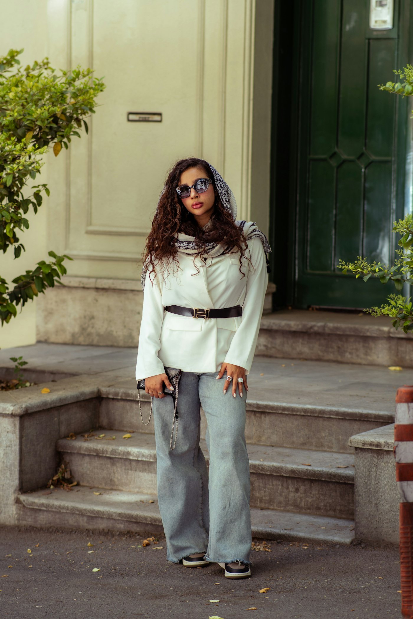 Woman in a white blazer and grey trousers standing on steps