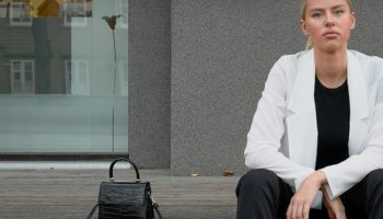 Woman in a white blazer sitting on steps, loafer outfit idea