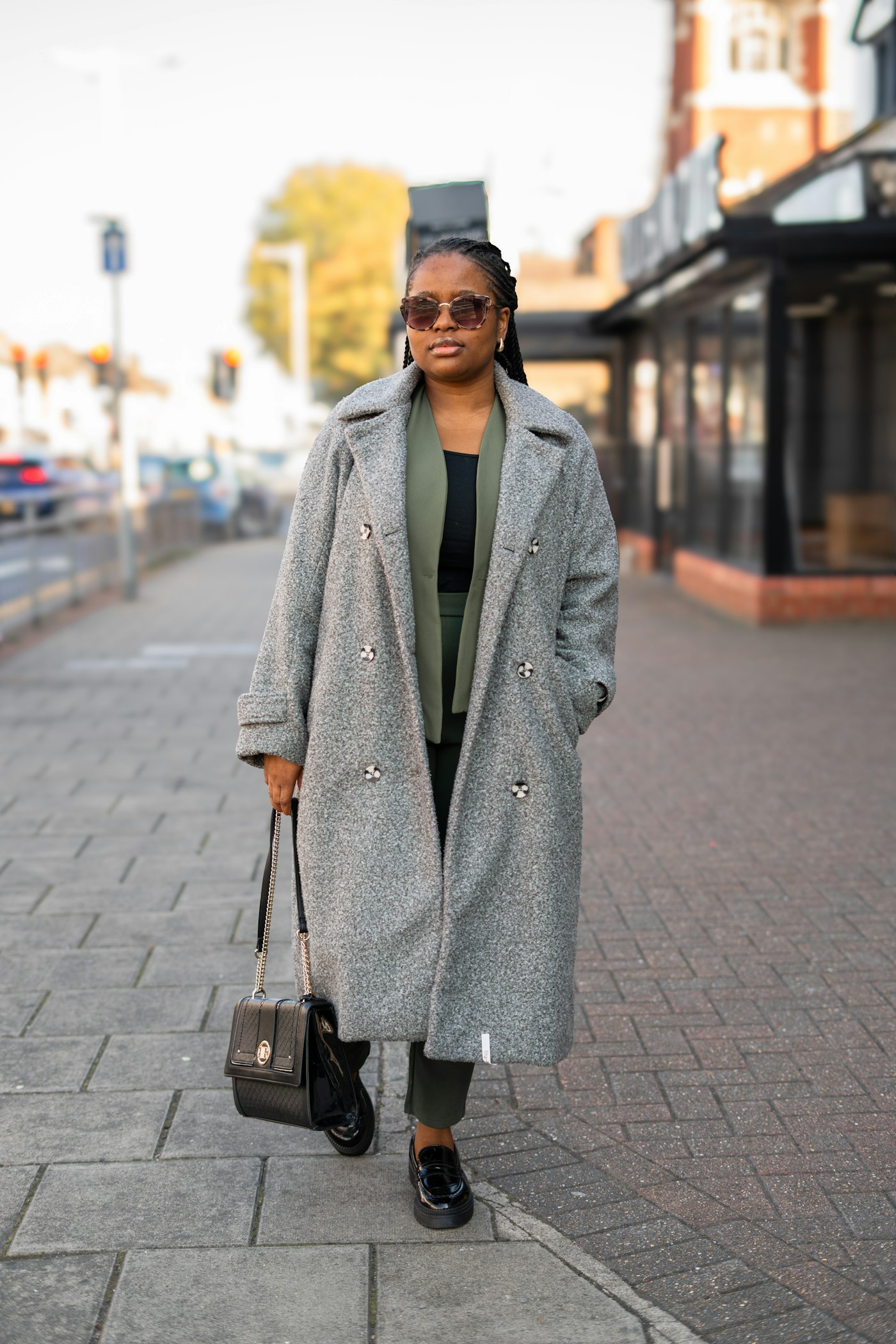 Woman in a grey coat walking on a sidewalk