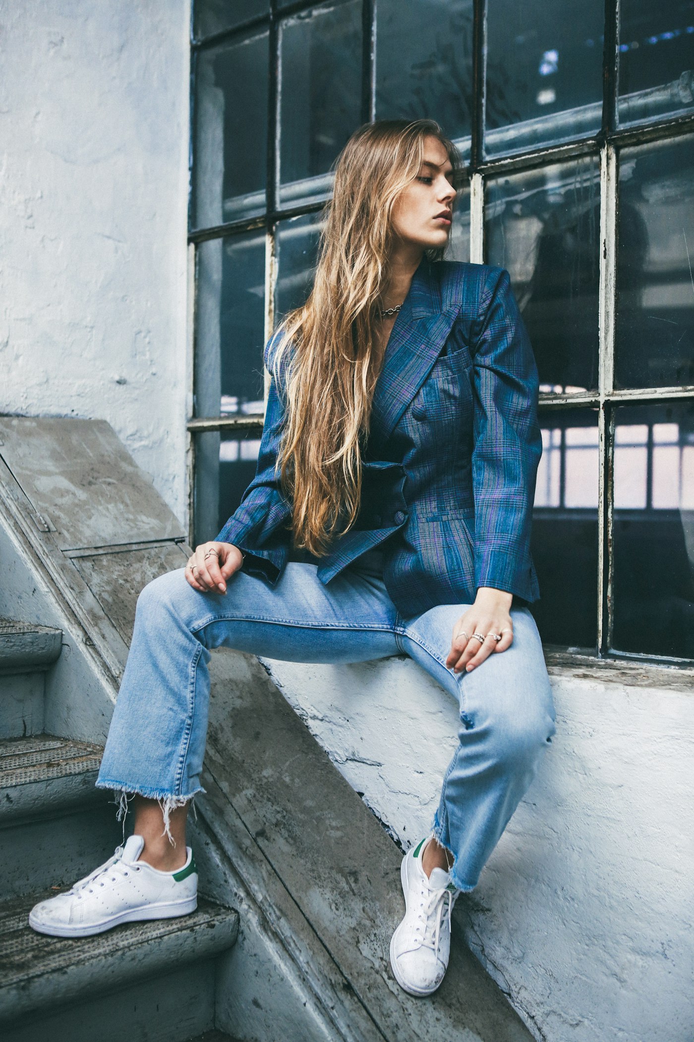 Woman sitting on a window ledge near a staircase wearing loafers