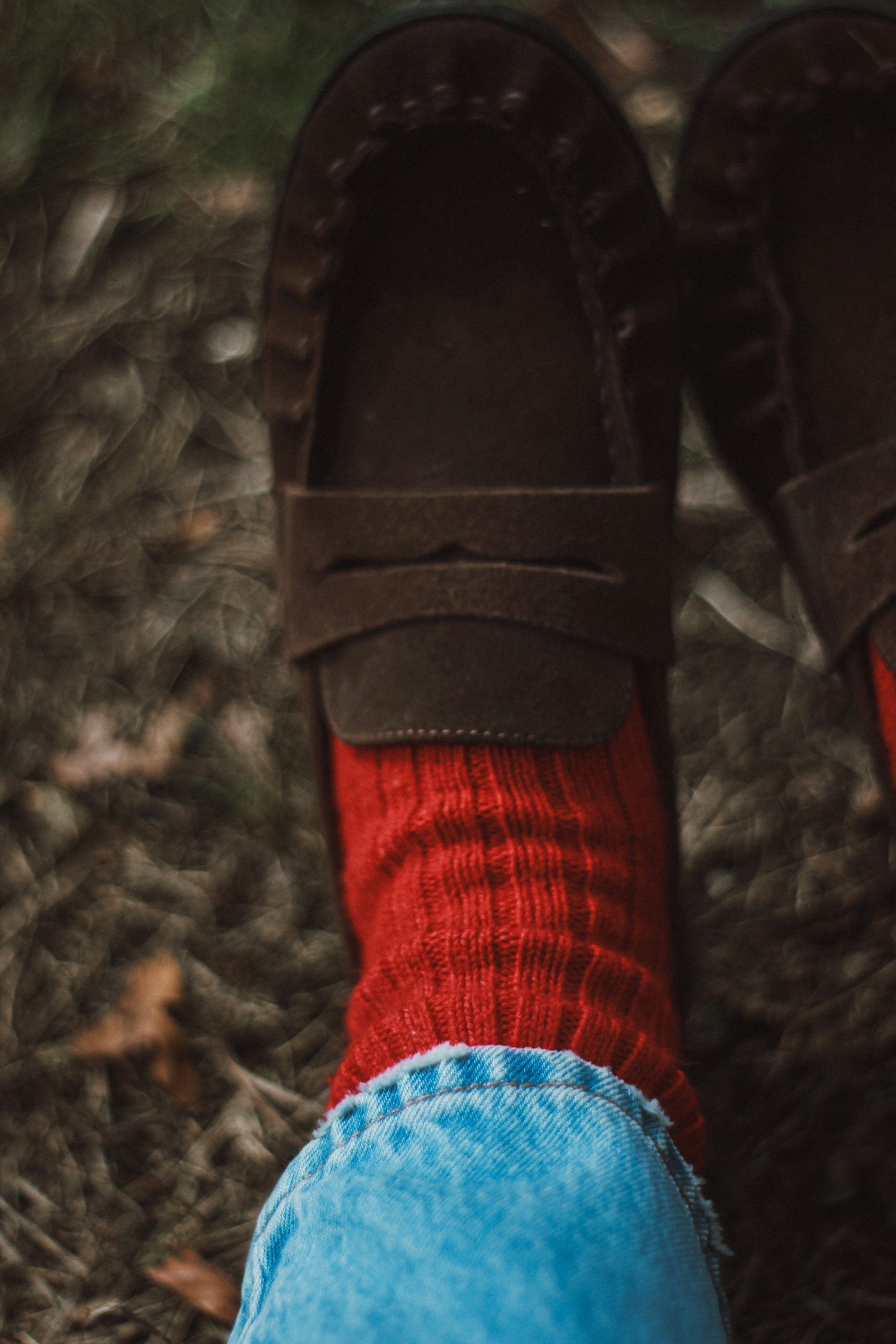 Brown loafers with red socks and blue jeans